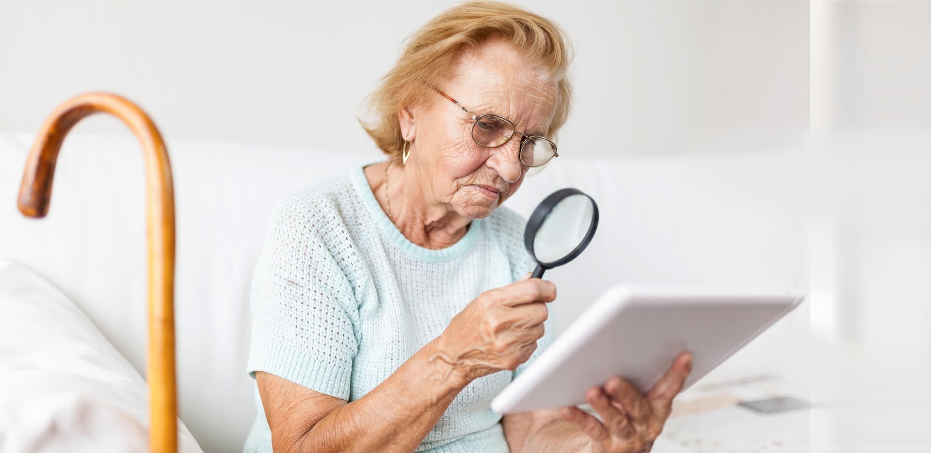 An Elder Women Looking Through A Lens To A Tablet