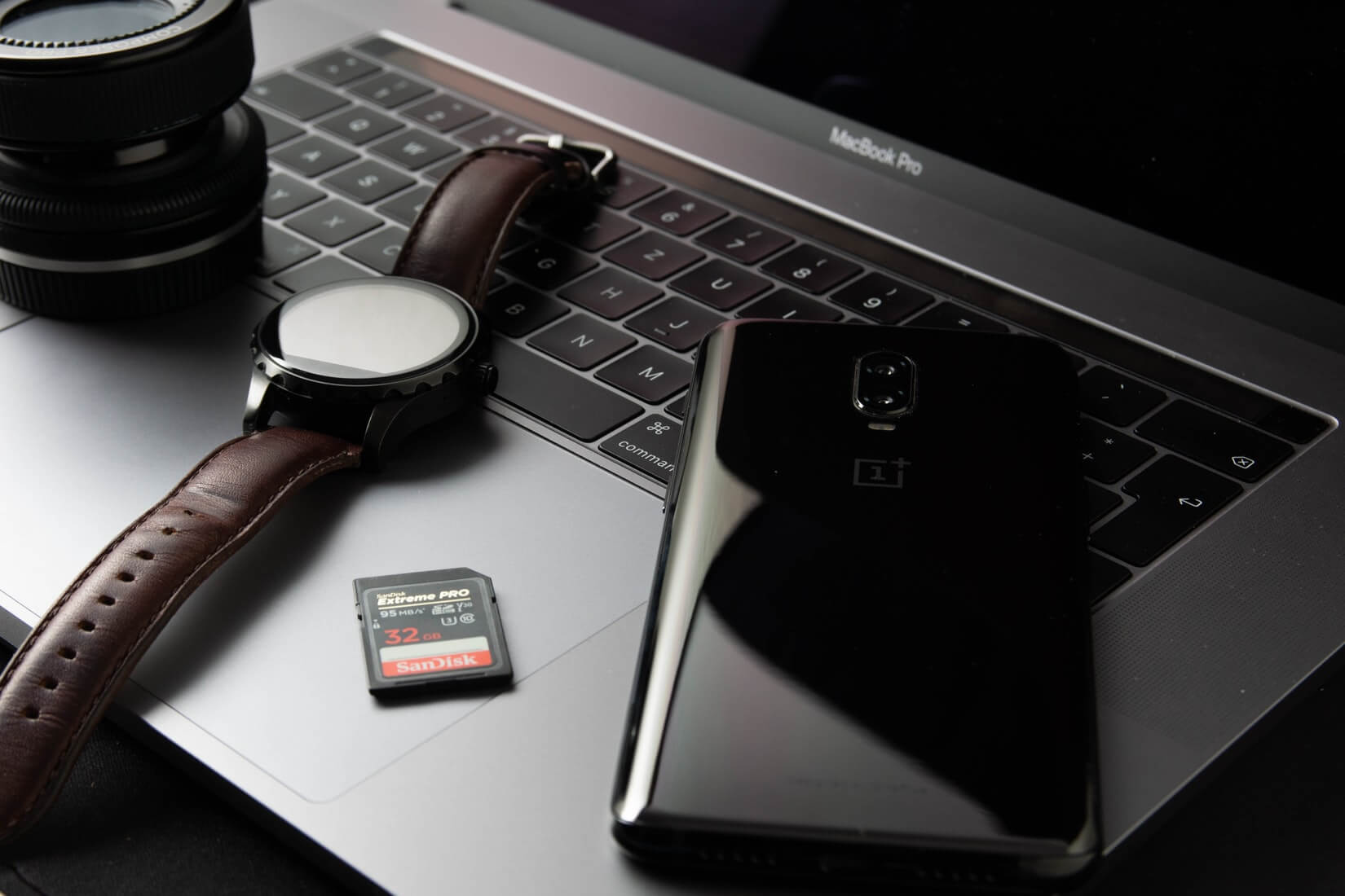 A Camera Lens | A Macbook pro | Watch | 32 GB SD Card | Oneplus Smartphone
