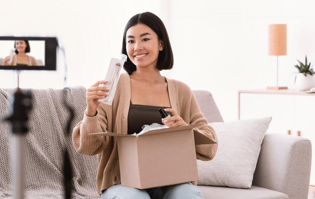 a lady unboxing a beauty product and shooting video on a camera