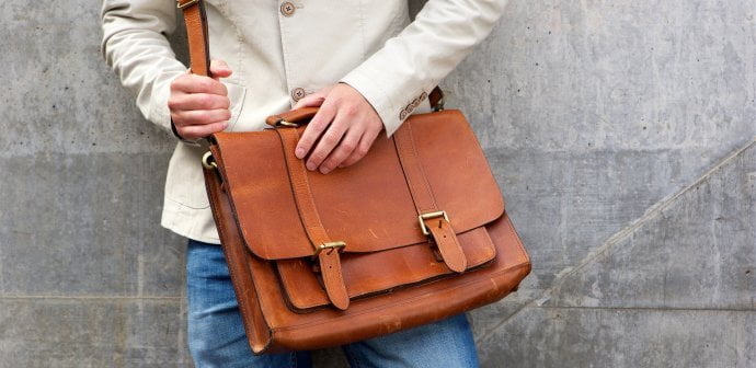 man with leather shoulder bag standing wall